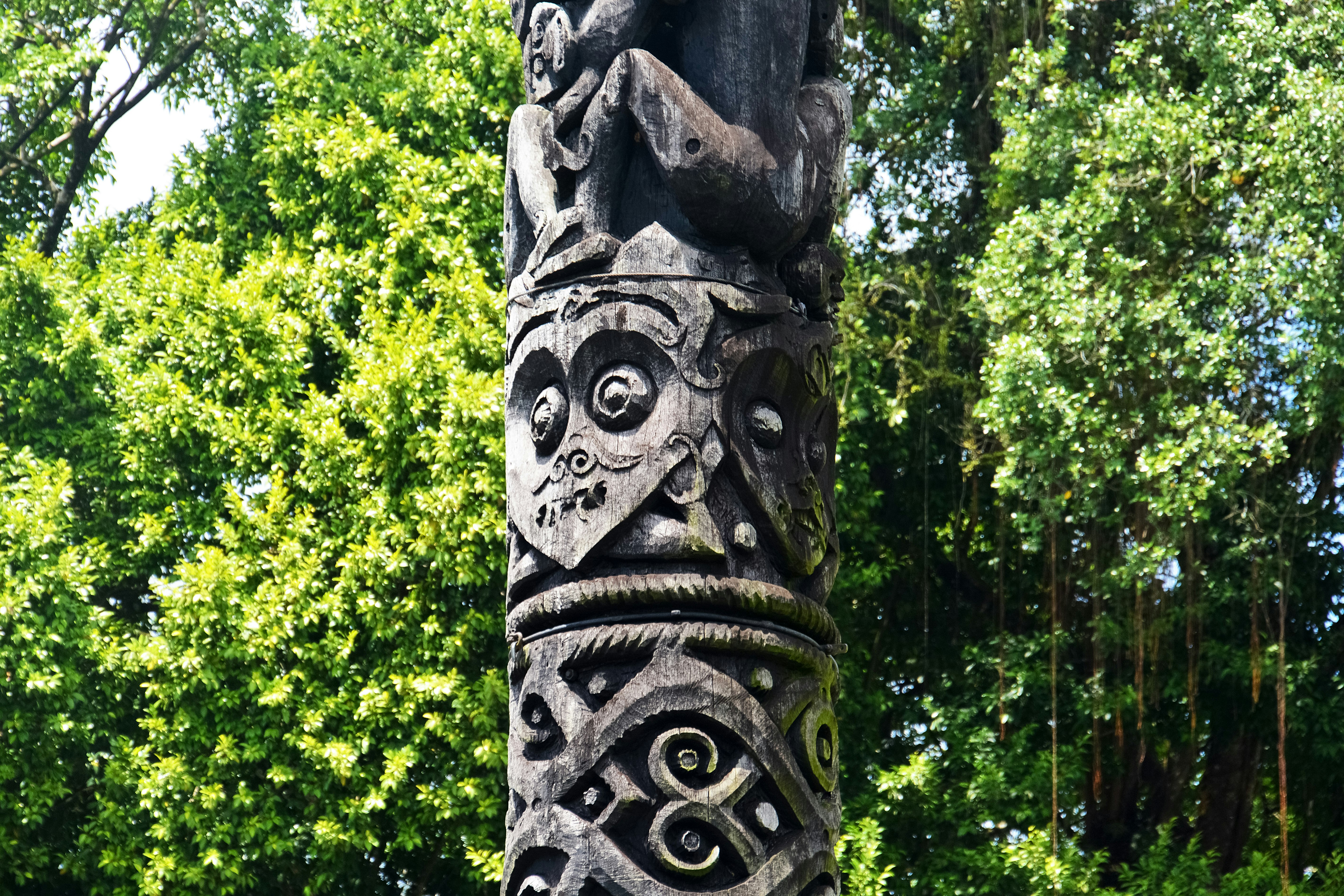 brown wooden statue near green trees during daytime